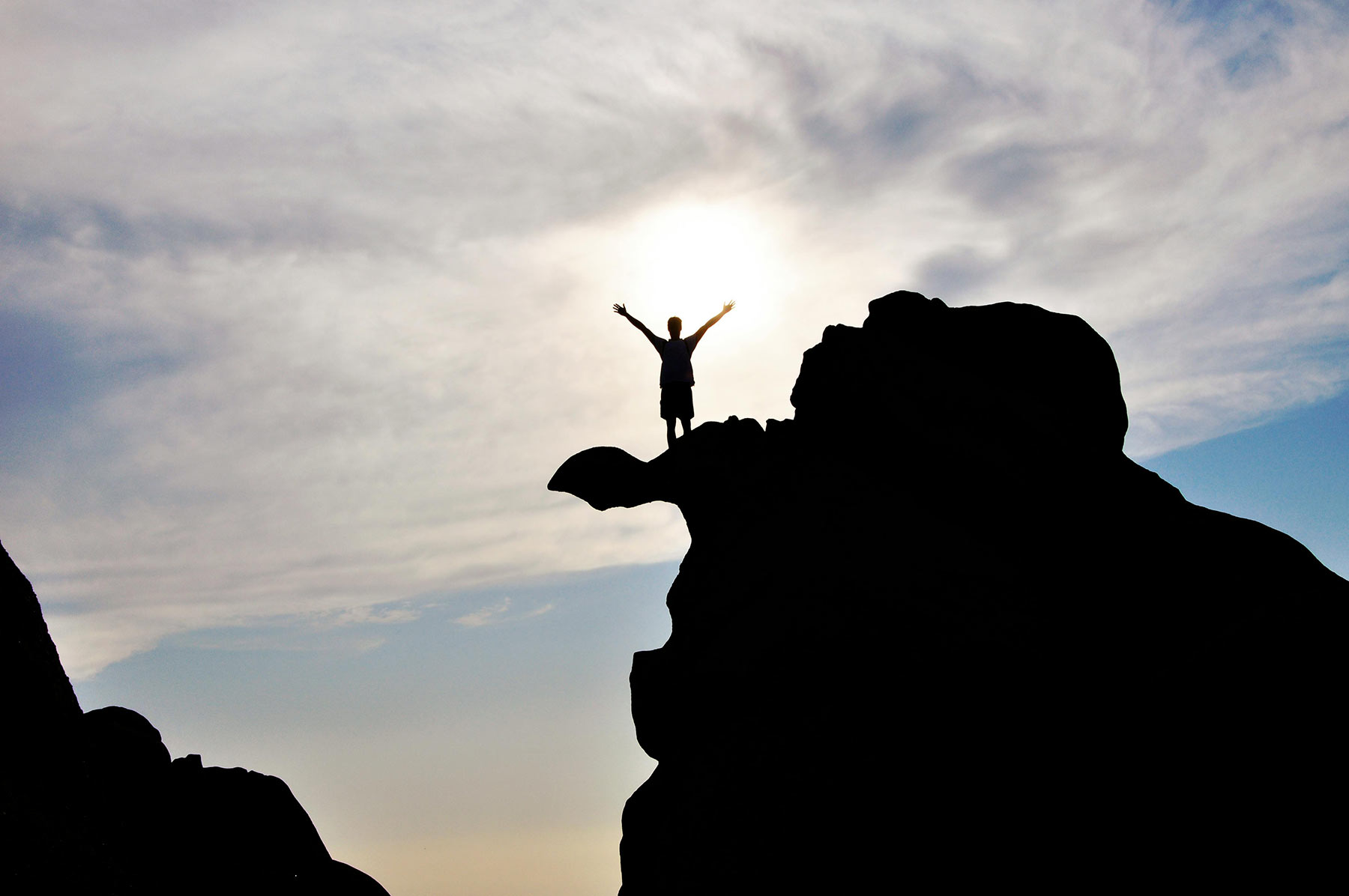 Silhouette of a person climbing a mountain