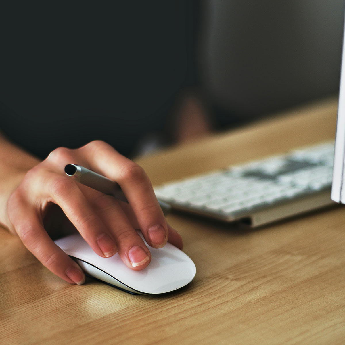 Woman holding a mouse in front of a computer